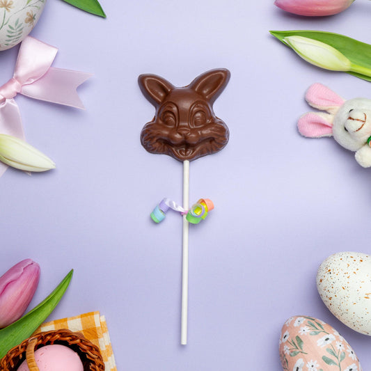 a chocolate bunny on a stick next to eggs and flowers