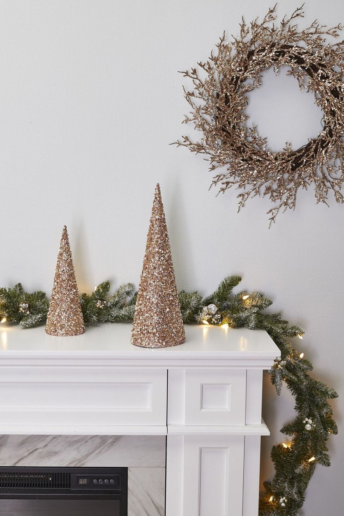 a white dresser with a wreath and two glittered trees