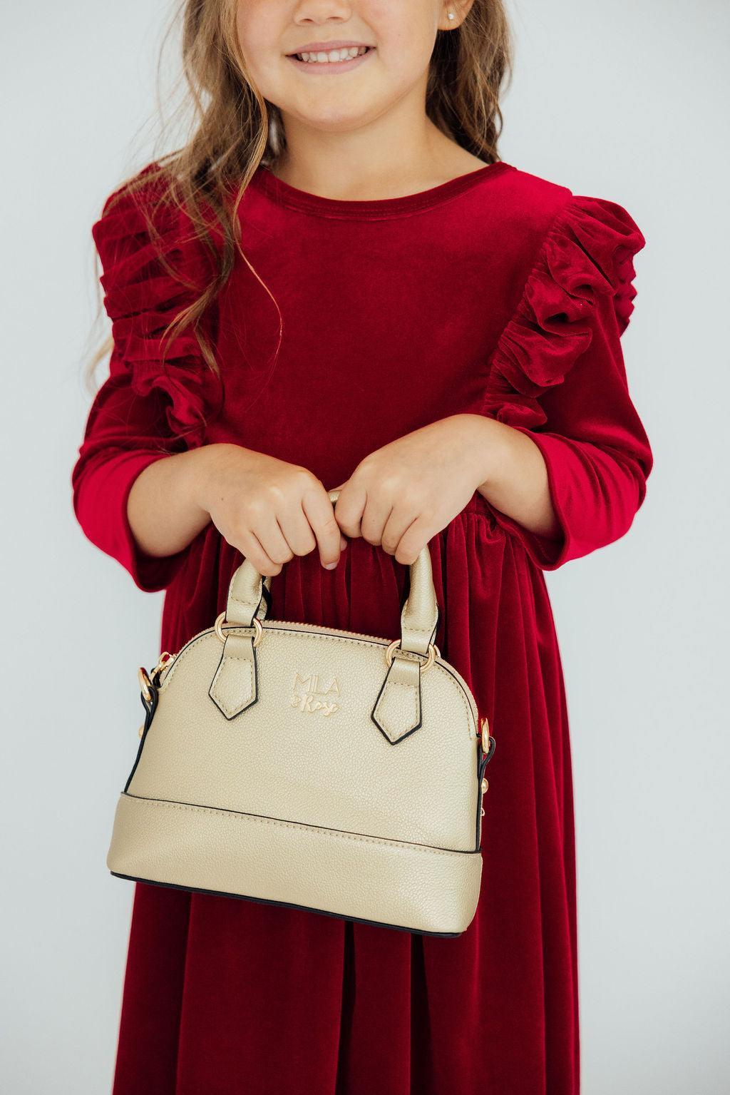 a girl holding a gold purse