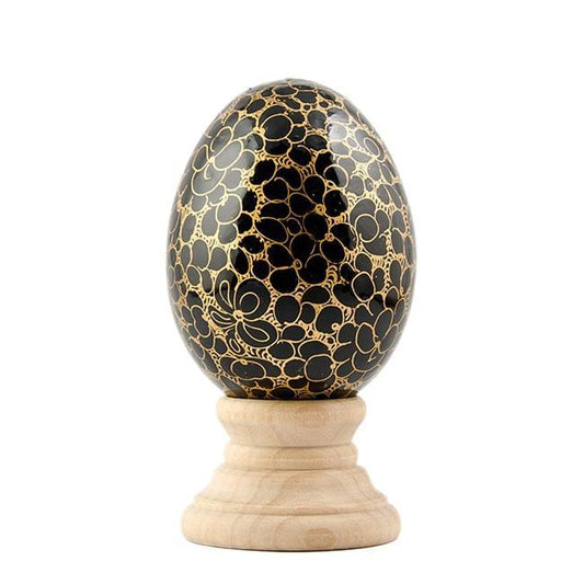 a black and gold egg on a wooden stand