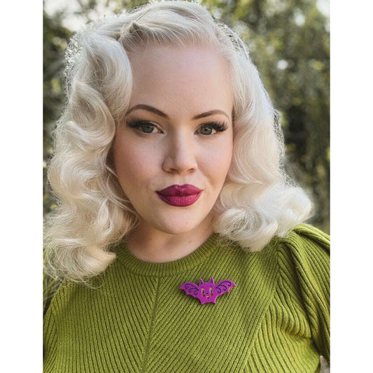 a woman with blonde hair and a bat pin