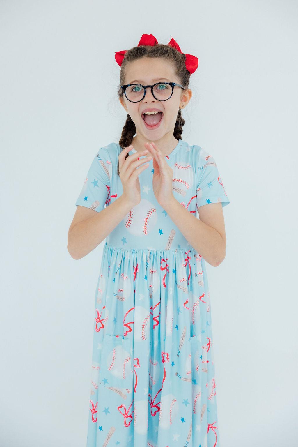 a girl with braids wearing glasses and a blue dress with red and white design
