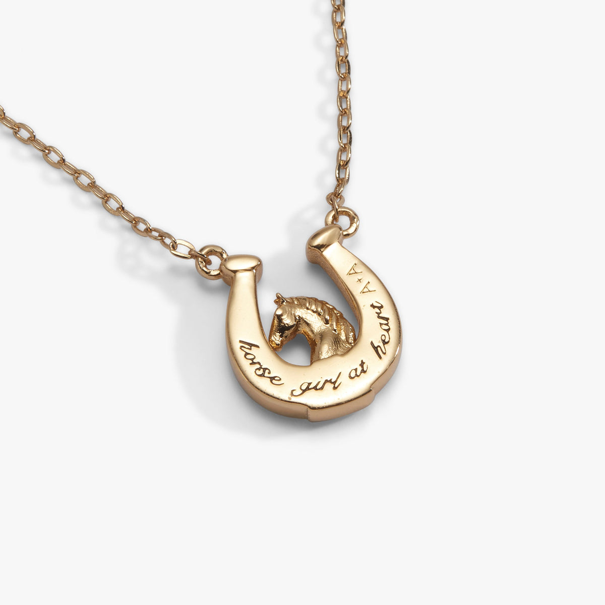 a gold horseshoe necklace with a horse on it