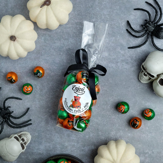a bag of candy next to white pumpkins