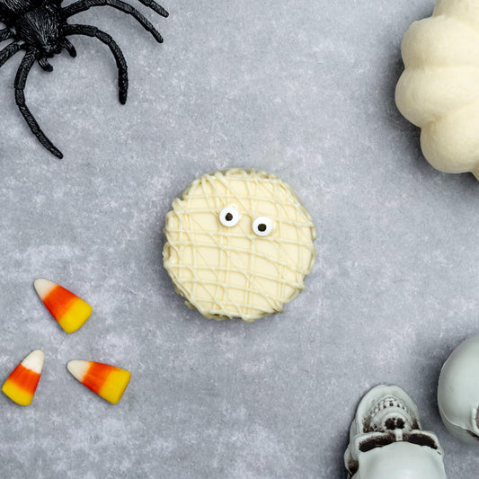 a white cookie with eyes and a white pumpkin and a white pumpkin and a black spider