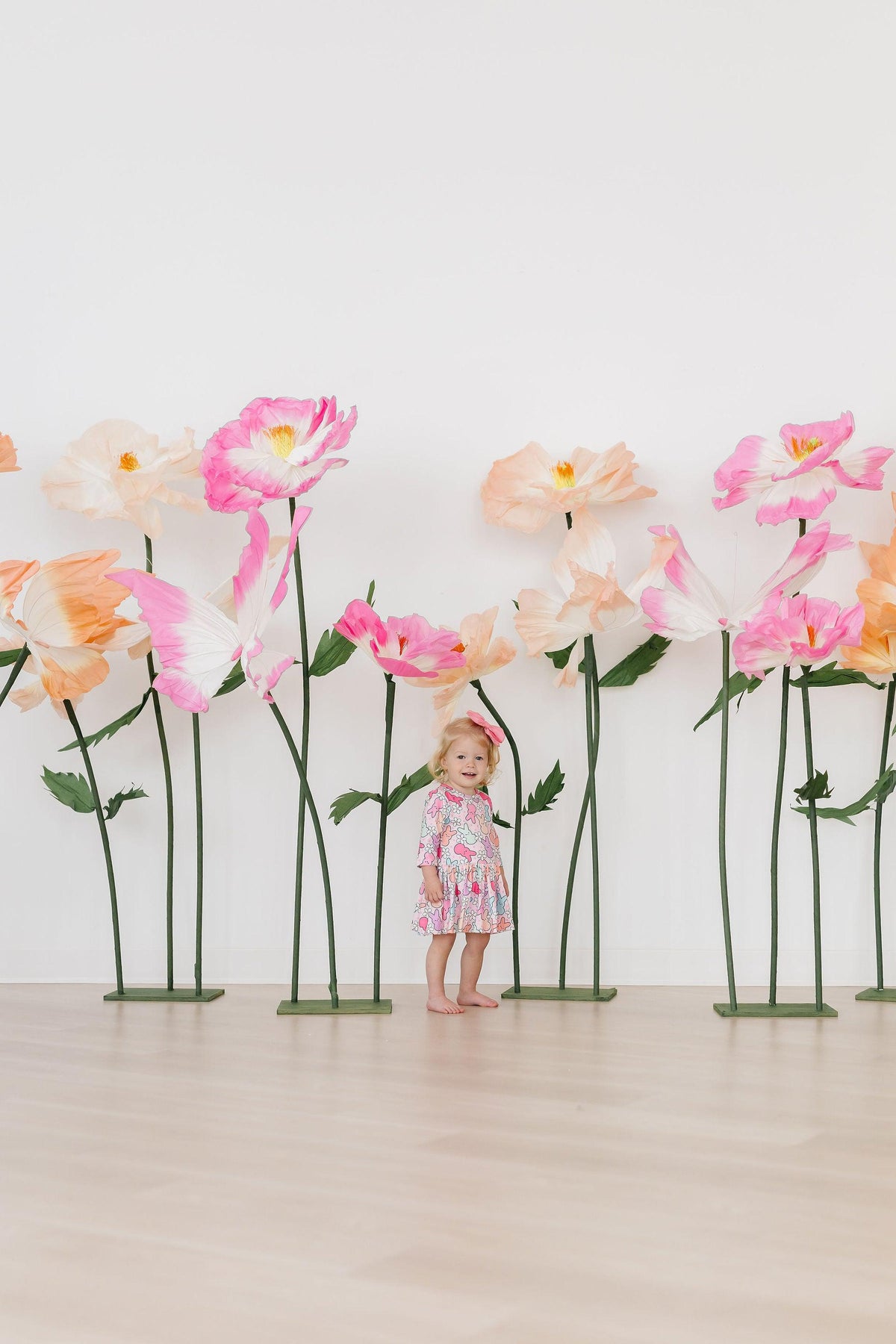 a girl standing in front of fake flowers