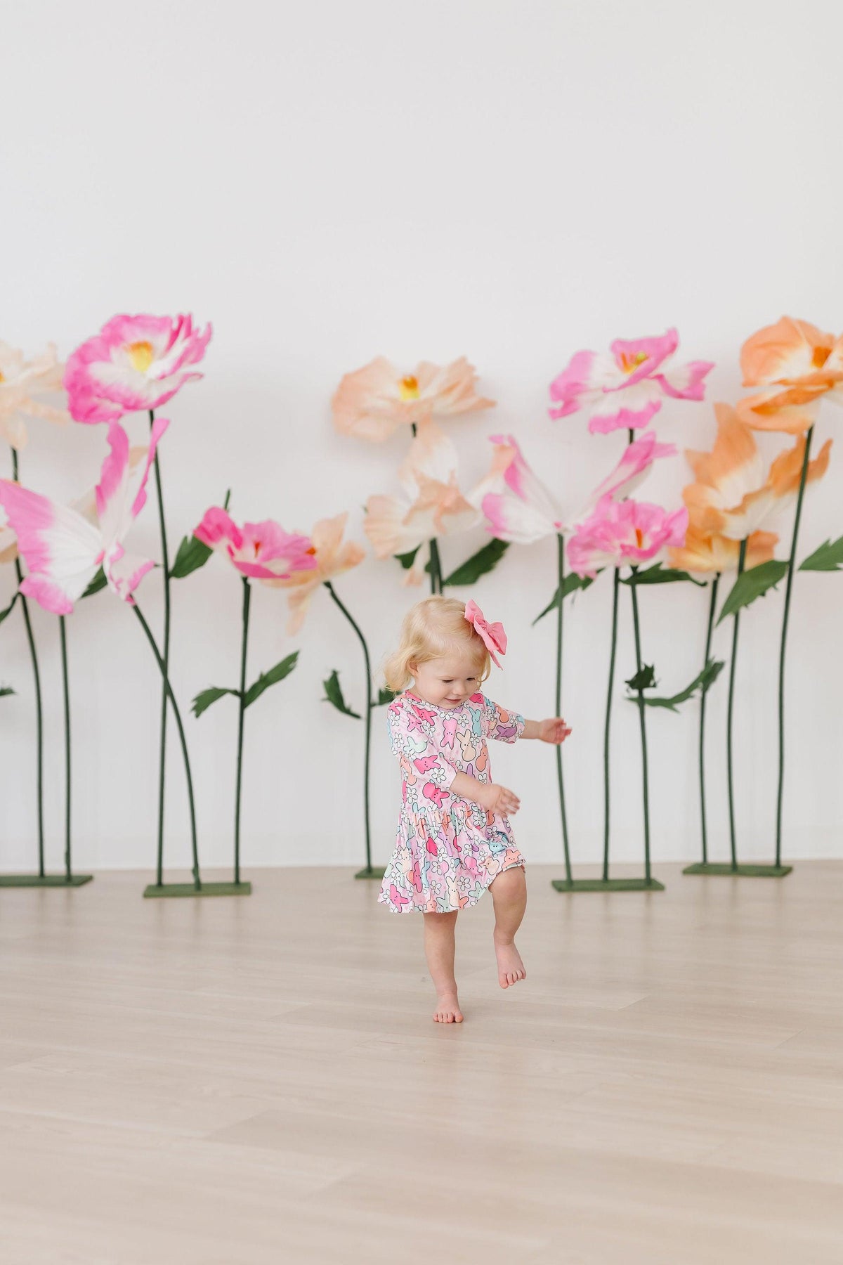 a girl in a dress in front of fake flowers