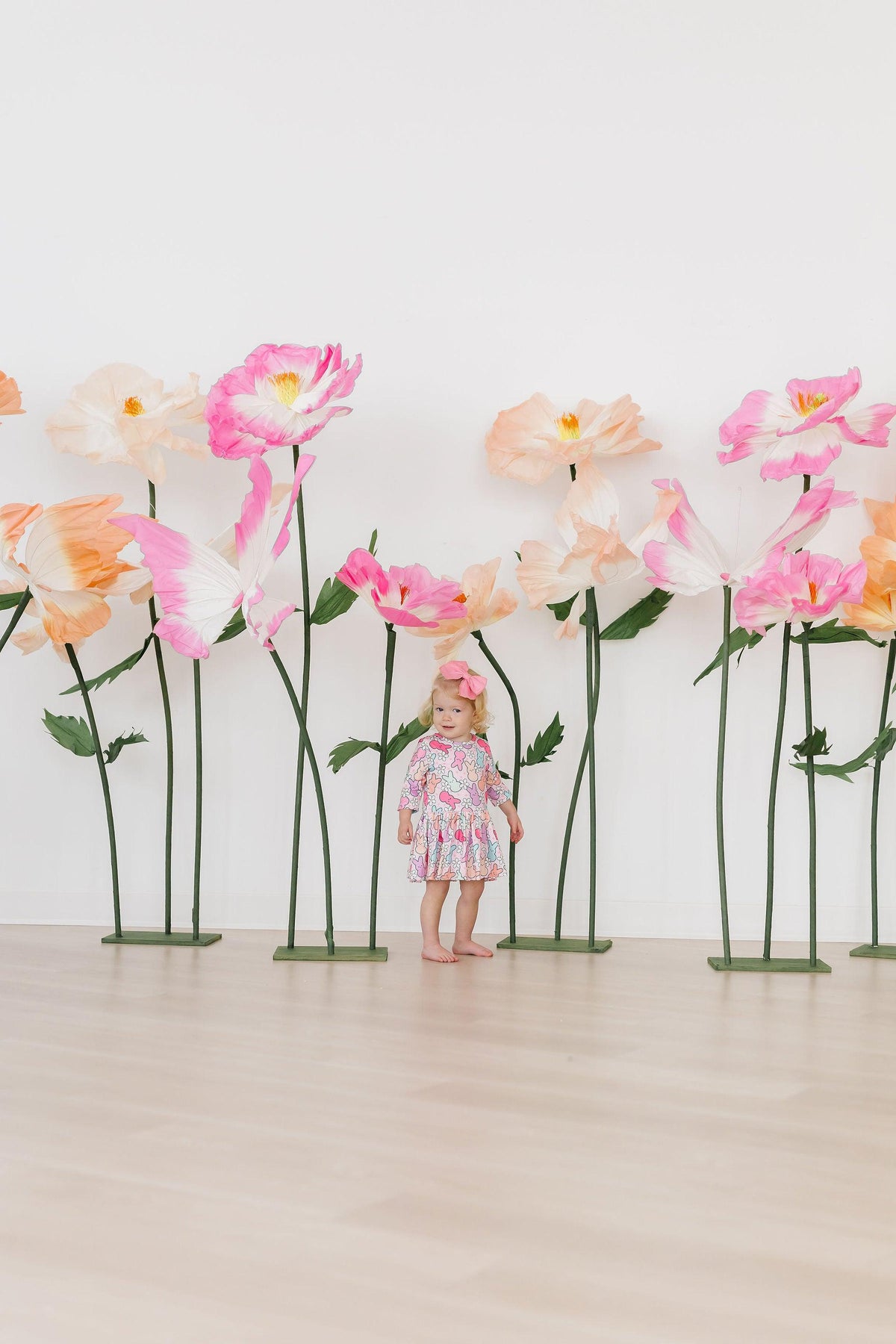 a child standing in front of fake flowers