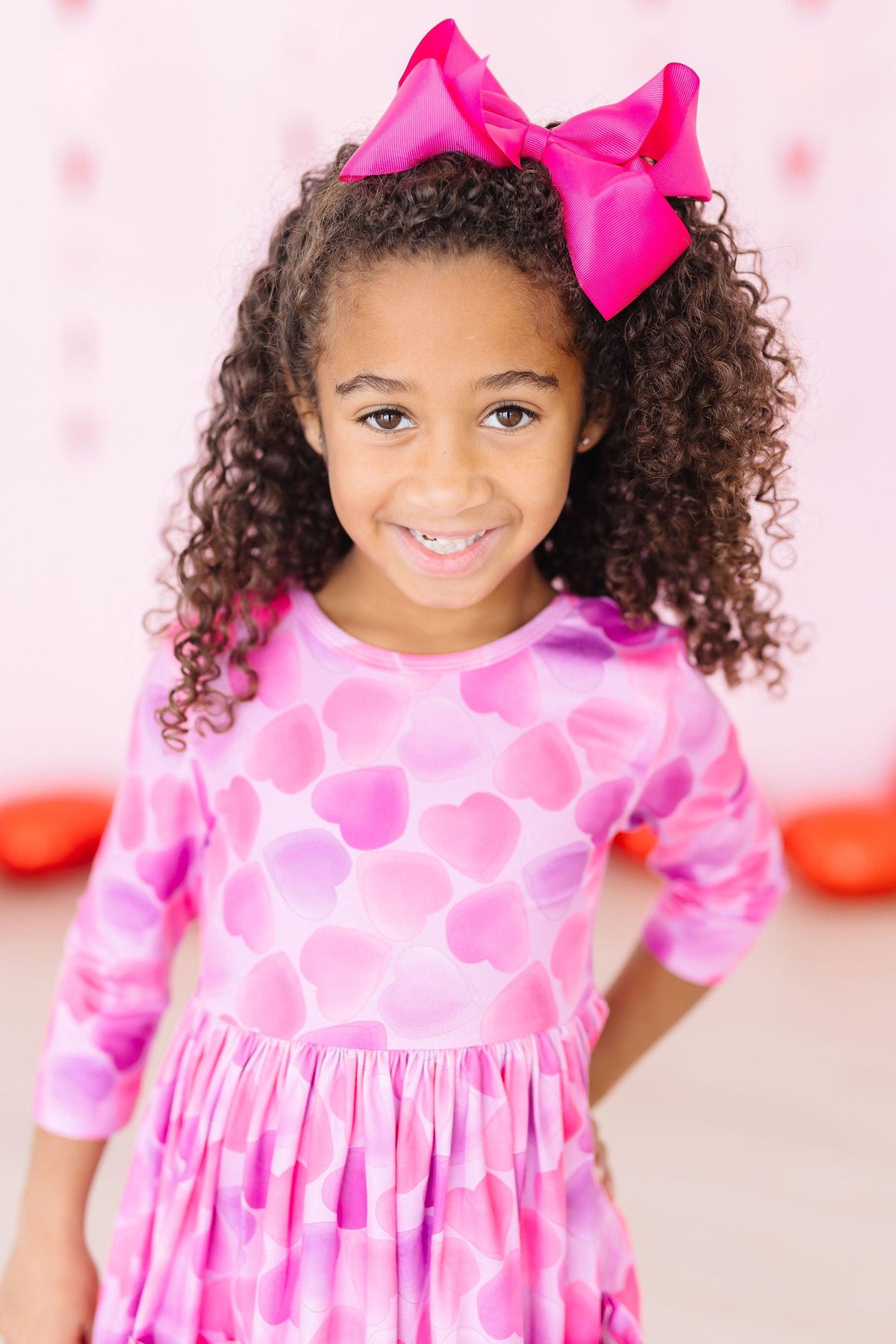 a girl with curly hair wearing a pink dress