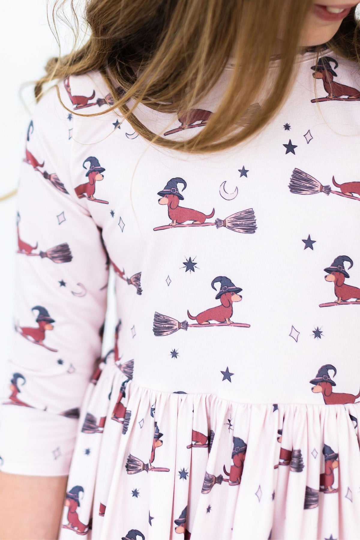 a child wearing a dress with a dog on broomsticks