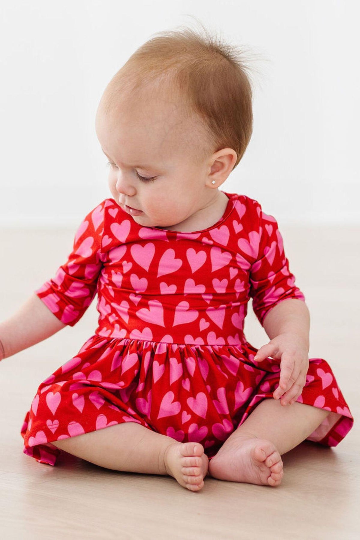 a baby girl in a red dress with hearts