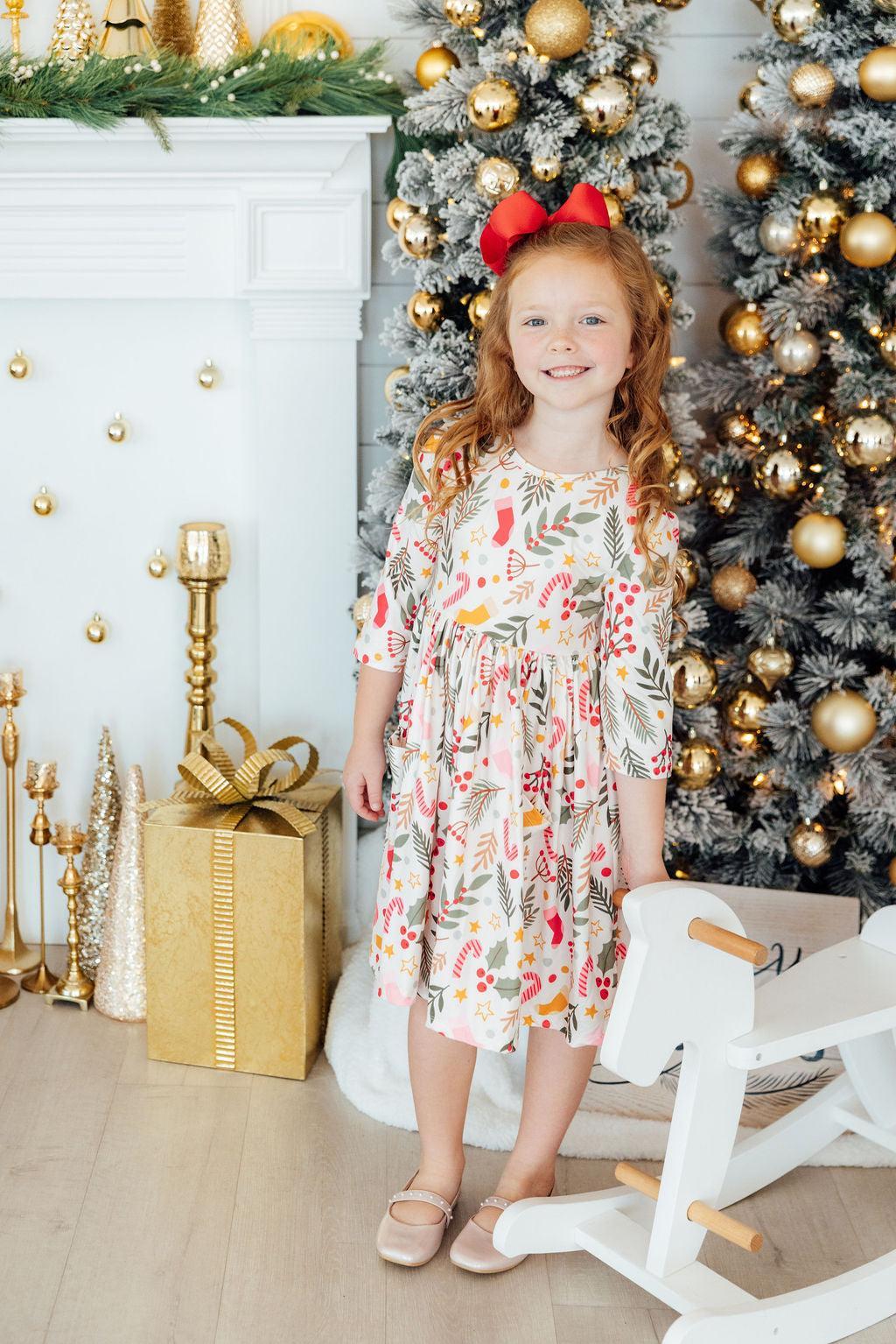 a girl standing in front of a christmas tree