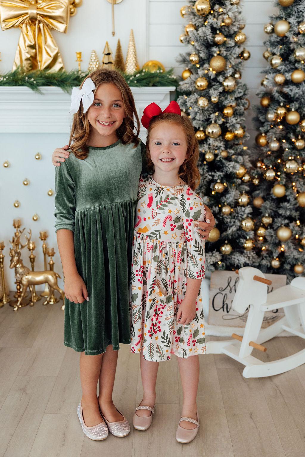 two girls standing in front of a christmas tree