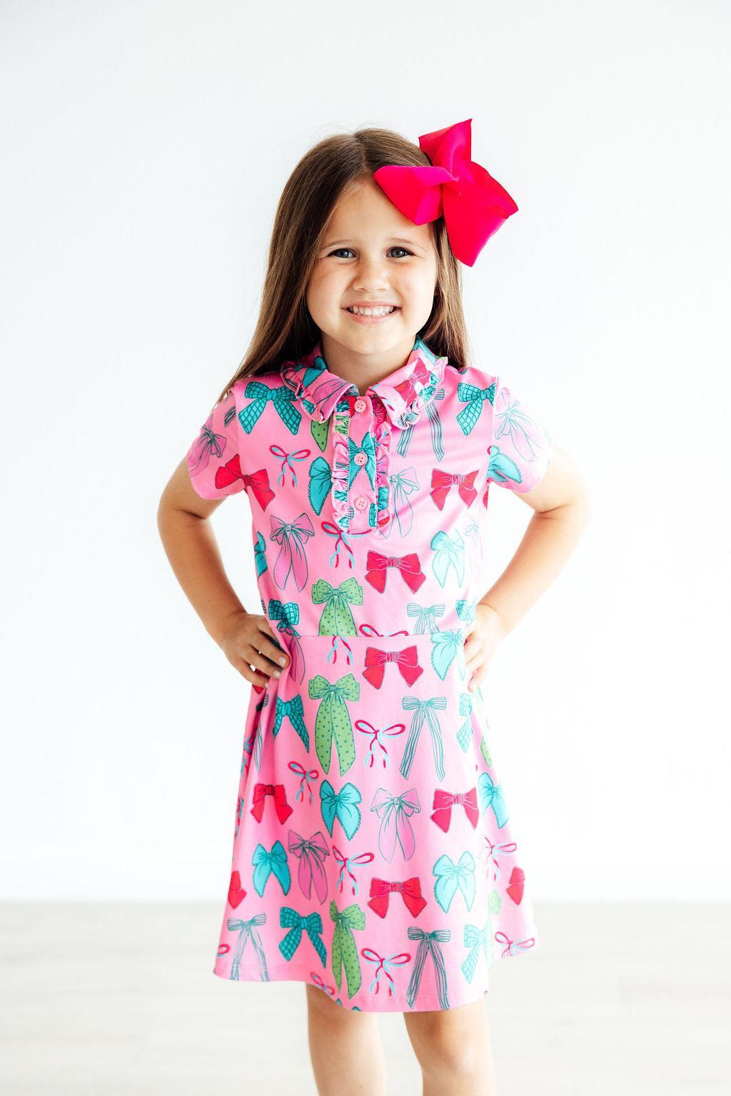 a girl wearing a pink dress with a red bow