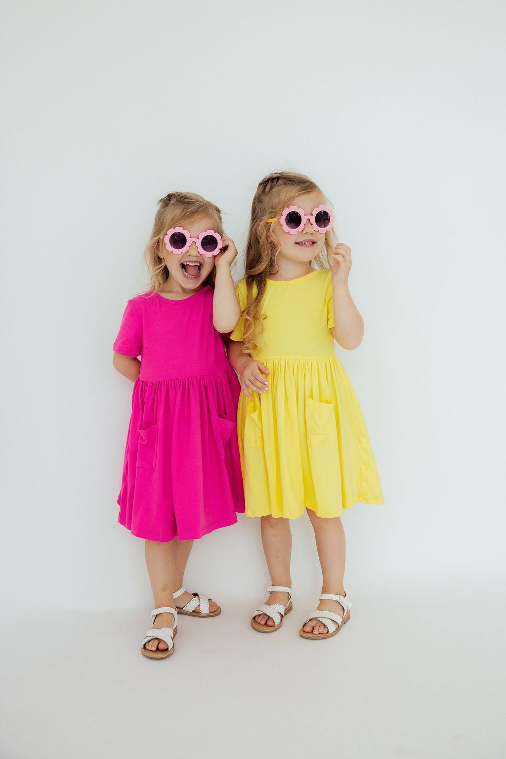 two girls wearing pink and yellow dresses and sunglasses