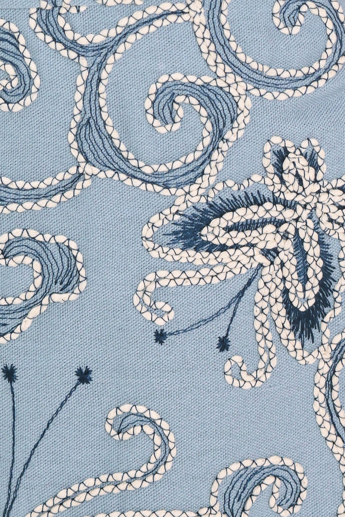 a close up of a blue fabric with white and black embroidery