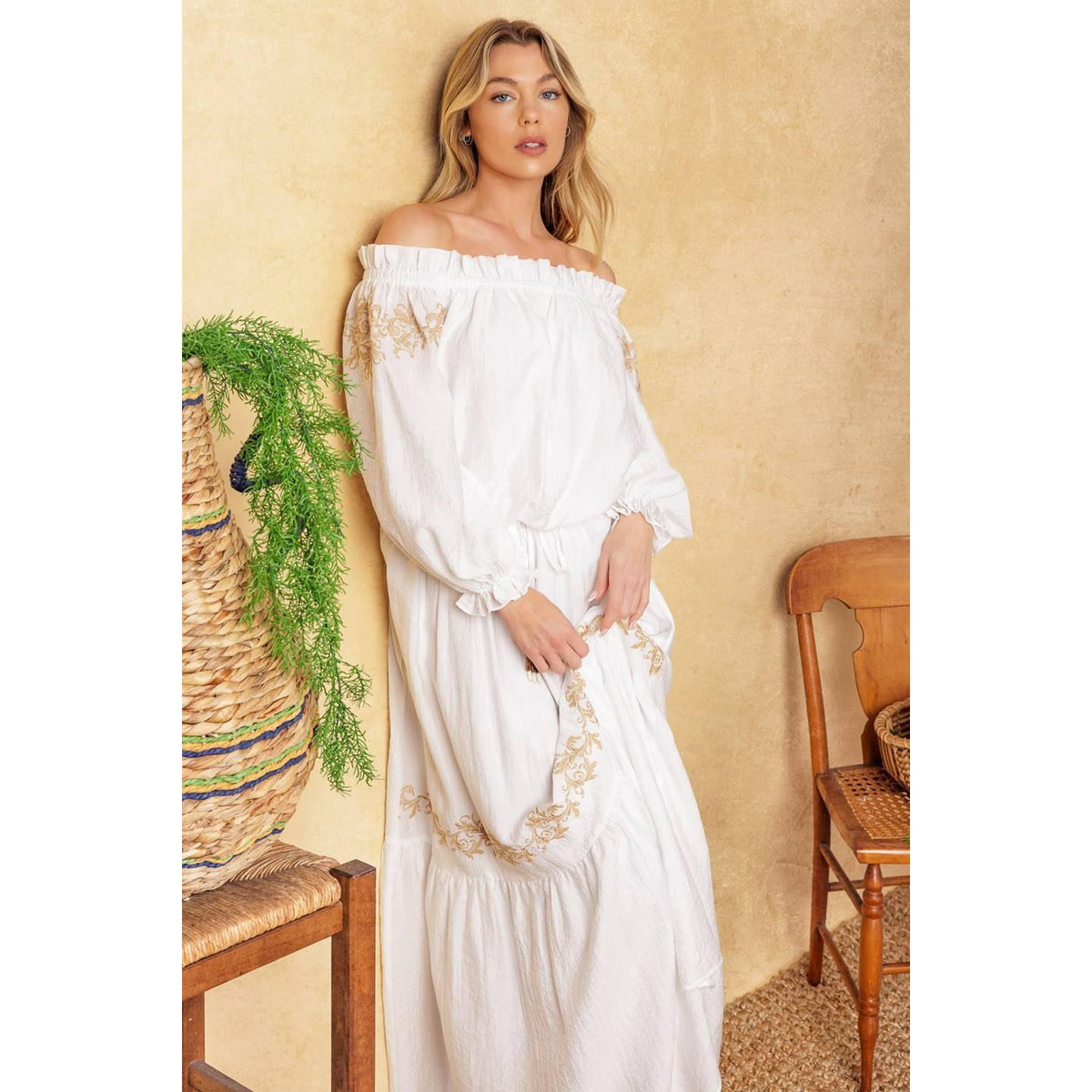 a woman in a white dress leaning against a wall