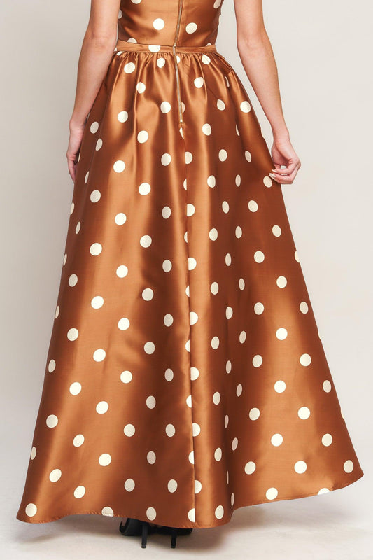 a woman wearing a long brown skirt with white polka dots