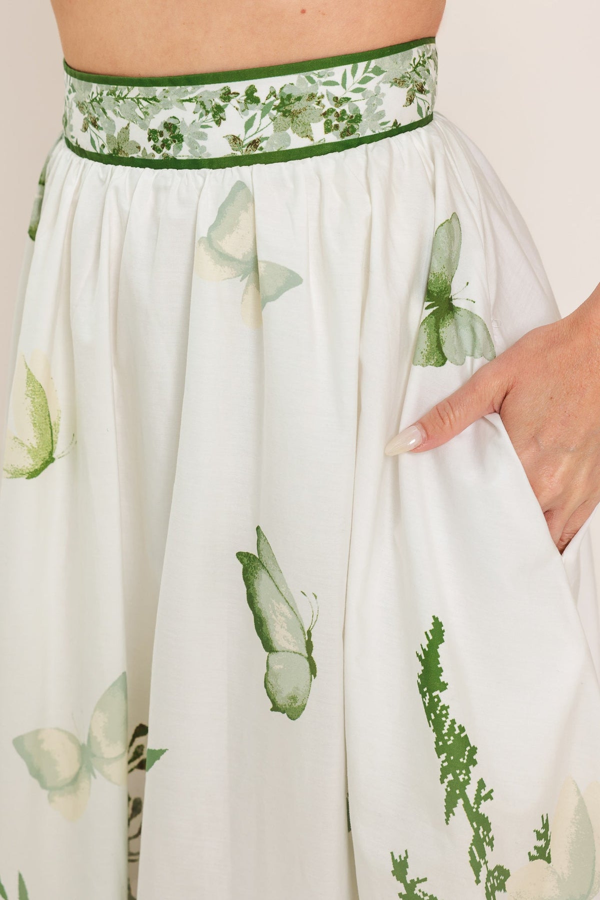 a woman's hand in a white skirt with butterflies on it