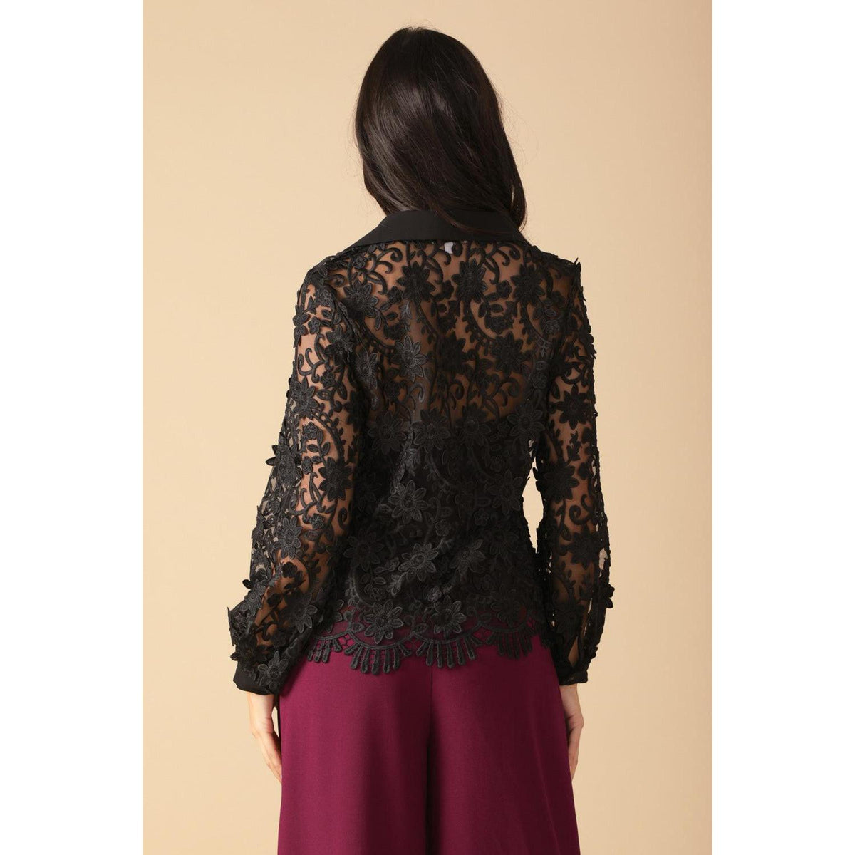 a woman wearing a black lace top and purple pants