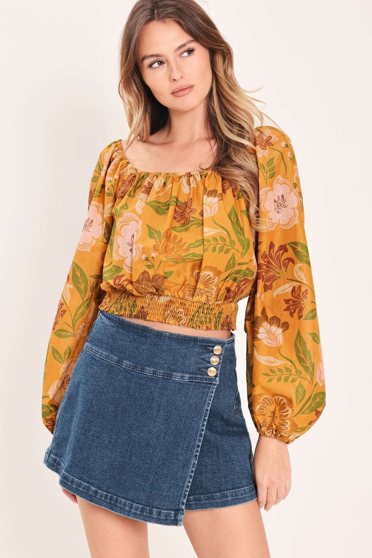 a woman in a yellow floral top and blue skirt