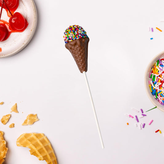 a chocolate ice cream cone with sprinkles on a stick next to a plate of cherries