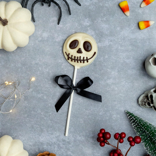 a lollipop with a black bow and a black ribbon surrounded by white pumpkins