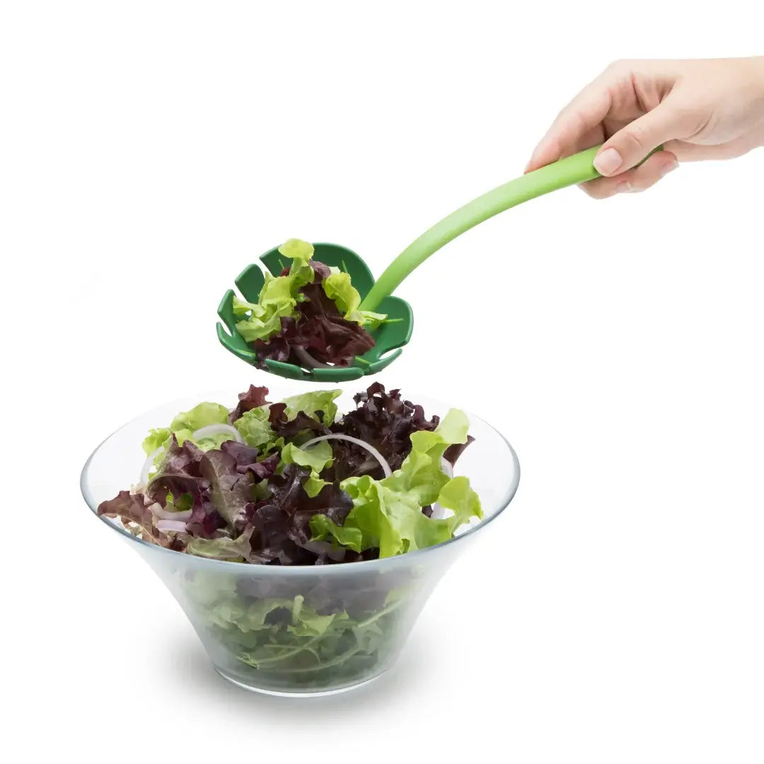 a hand holding a spoon over a bowl of salad