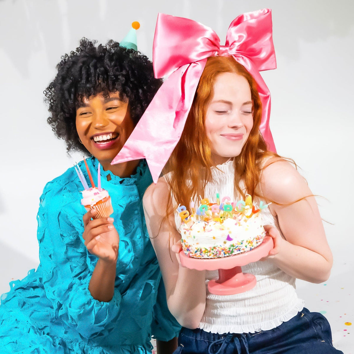 a group of women sitting on the floor with a cake and cupcakes