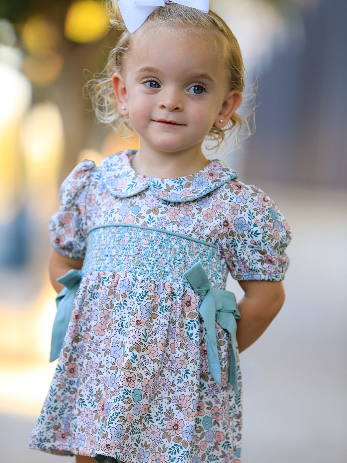 a girl with blonde hair wearing a floral dress