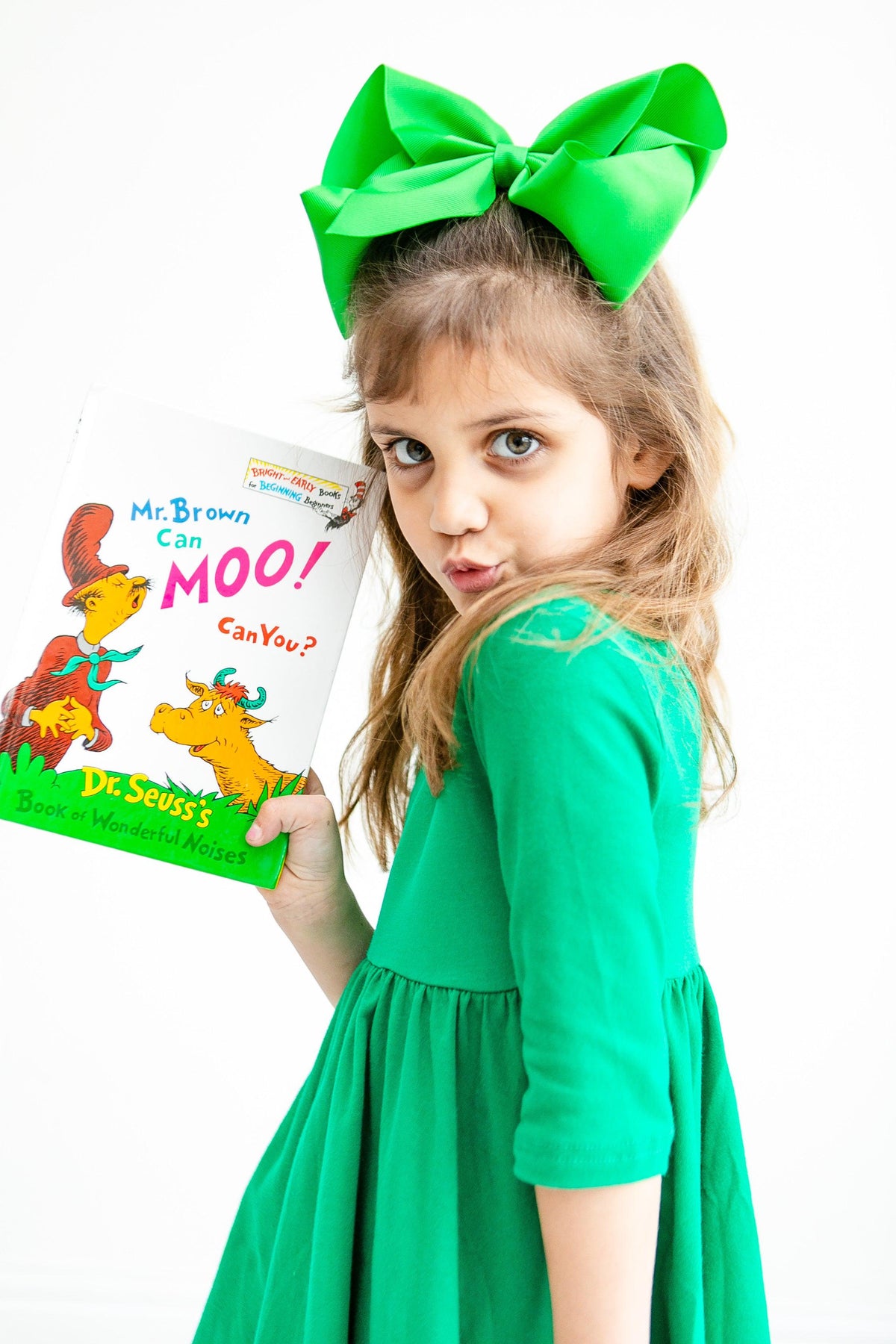 a girl in a green dress holding a book