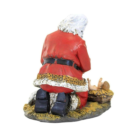 a statue of a santa claus kneeling on a manger