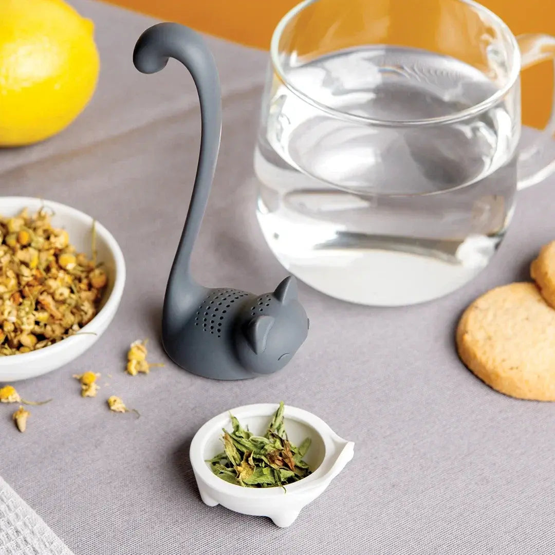 a cat shaped container with food in bowls next to a glass of water