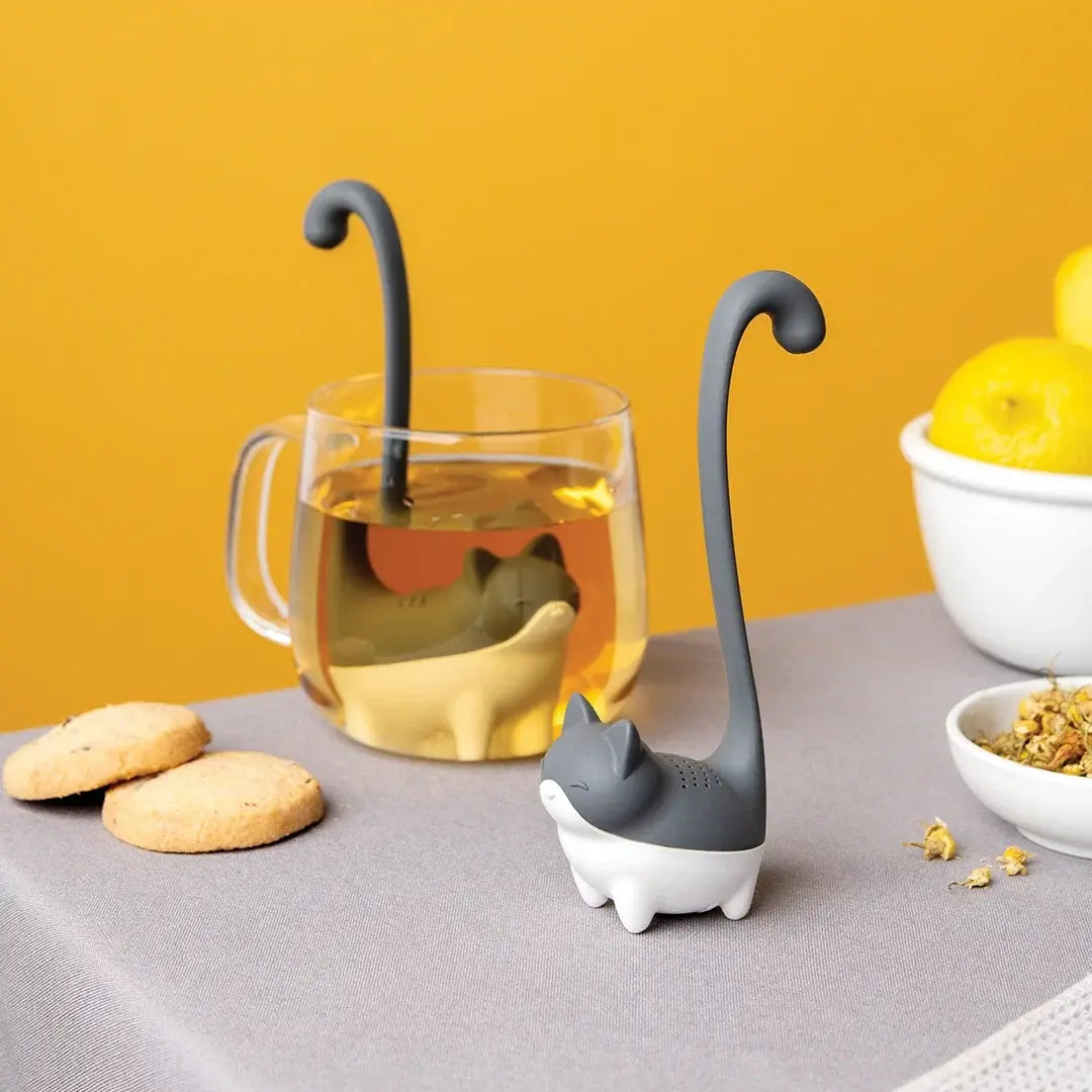 a cat shaped drink holder next to a glass of liquid