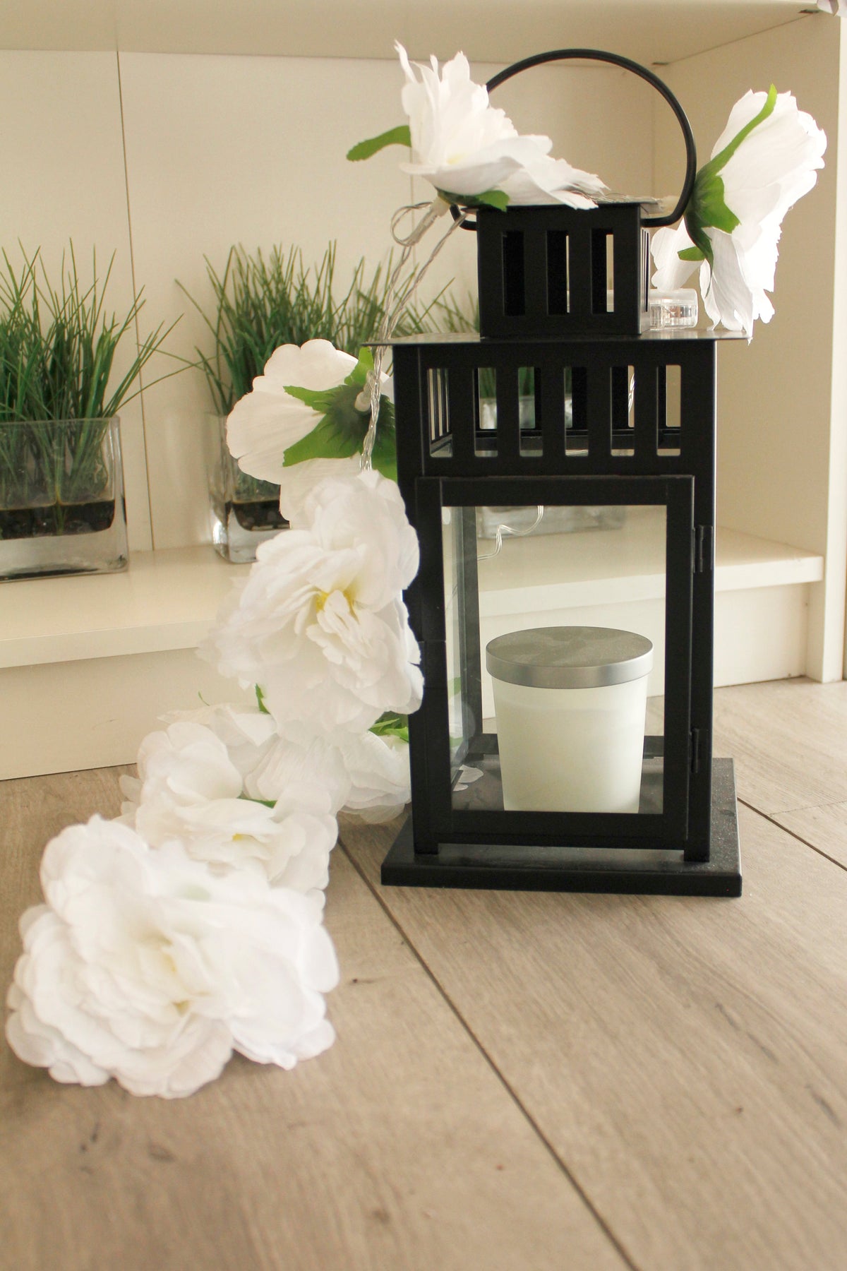 a black lantern with a candle and white flowers