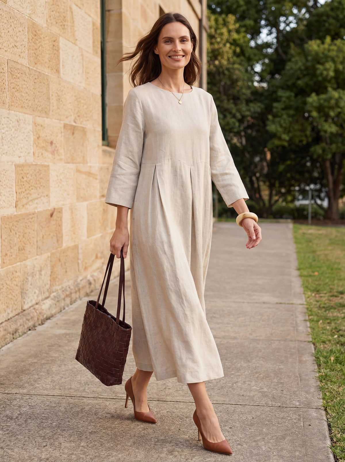 a woman in a long dress walking on a sidewalk