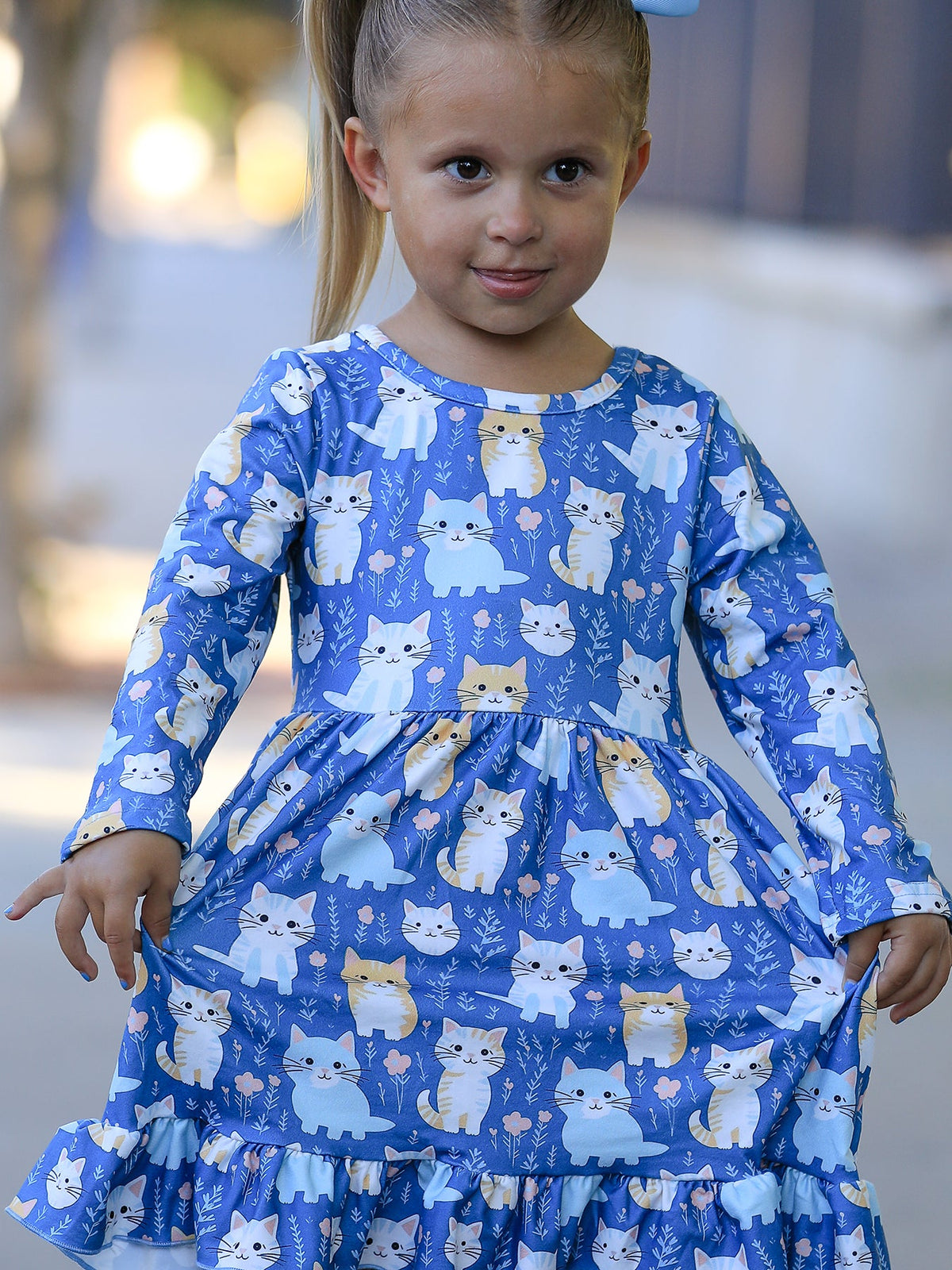 a girl in a blue dress with cats on it