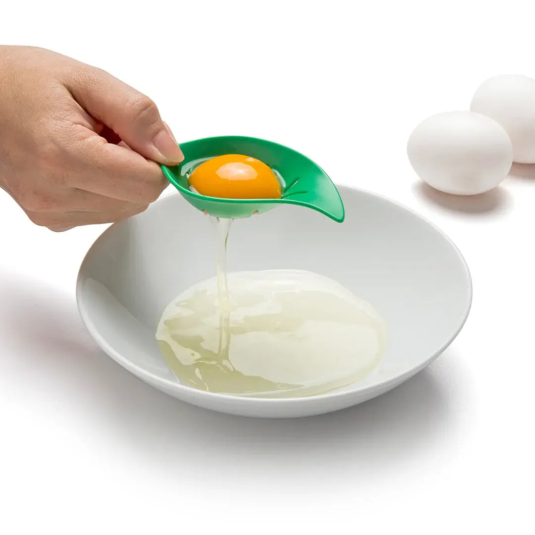 a hand holding a spoon over an egg being stirred by a bowl of eggs