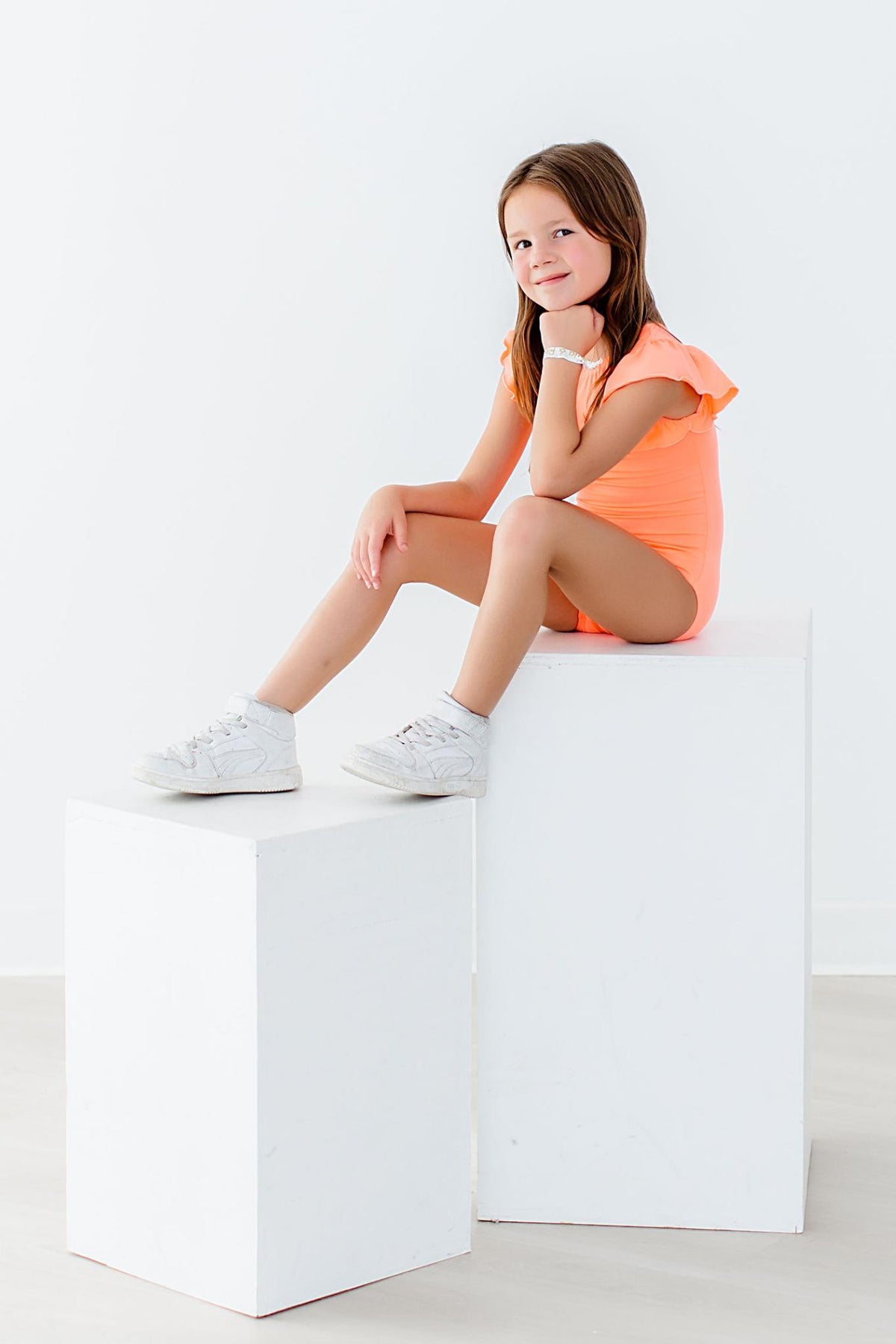 a girl sitting on a white cube