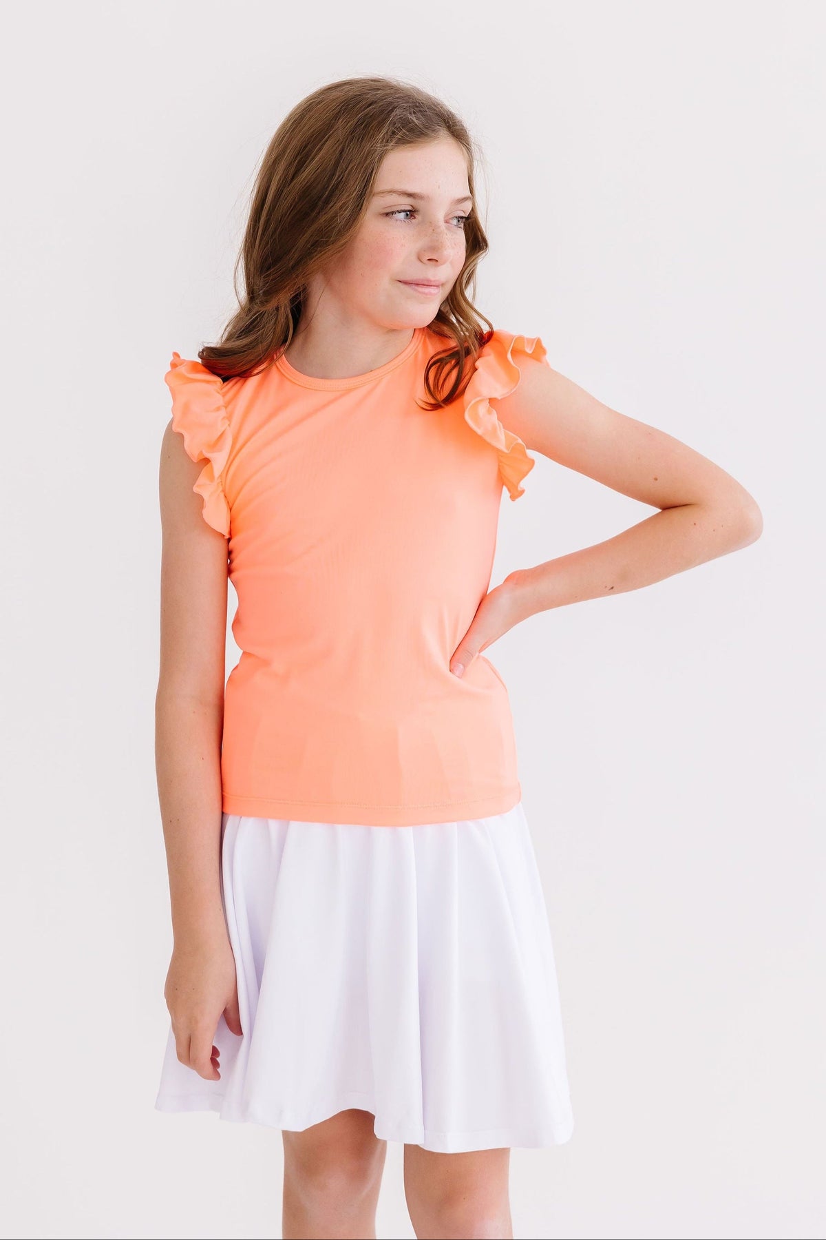 a girl in a white skirt and orange shirt