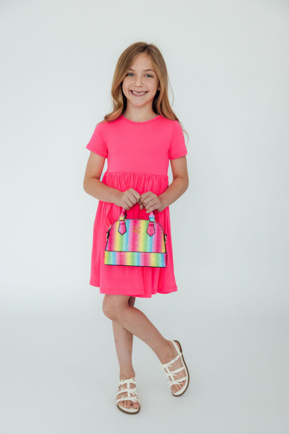 a girl in a pink dress holding a purse