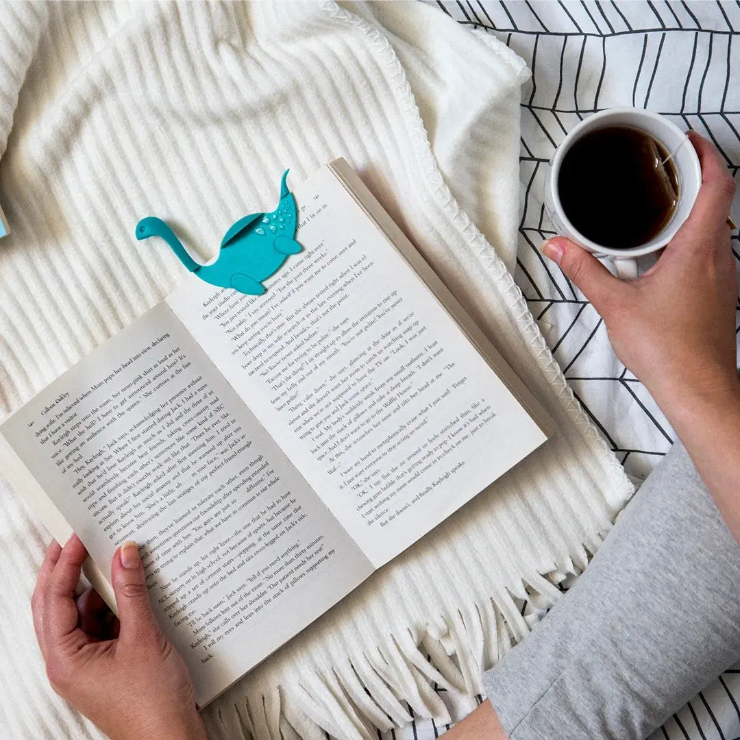 a person reading a book and a mug of coffee