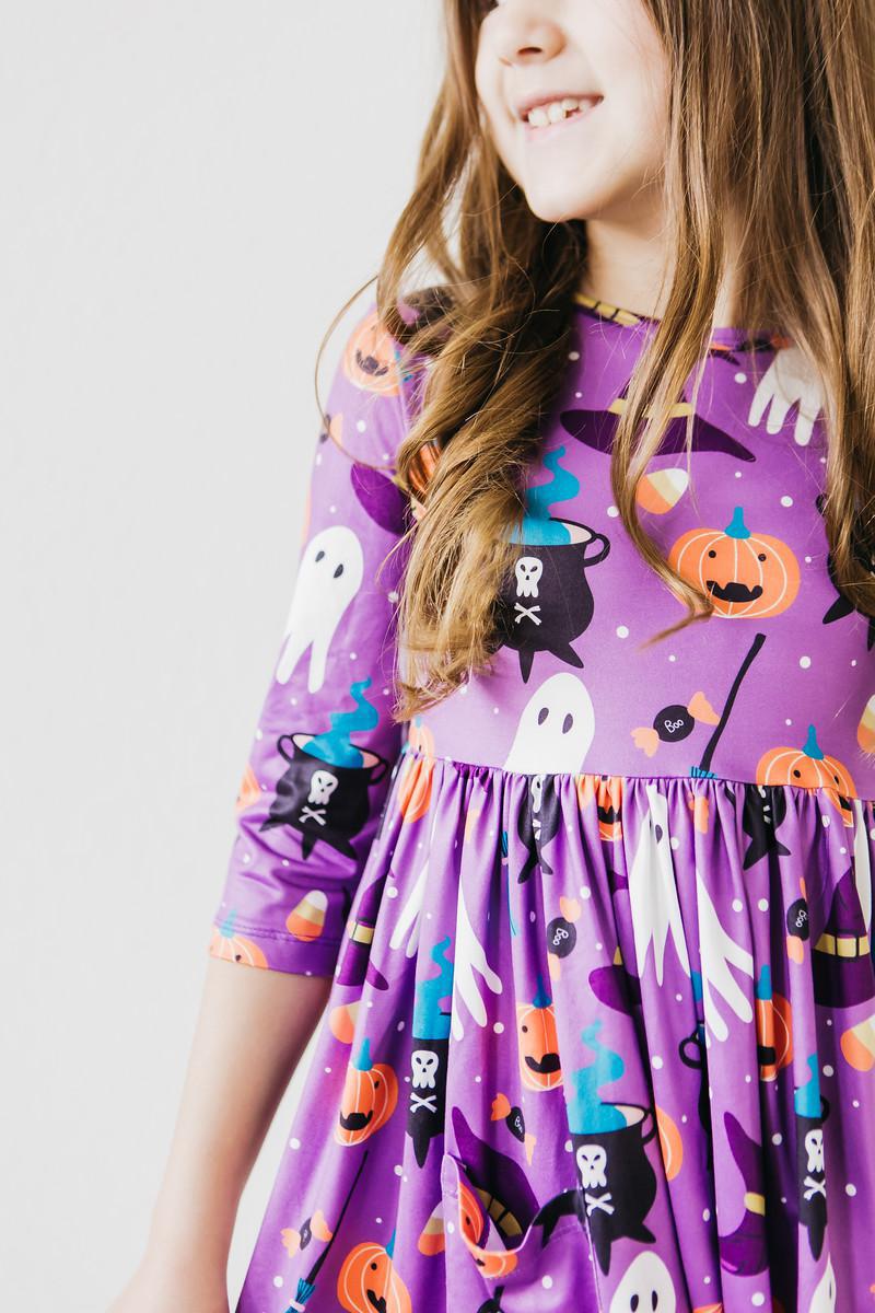 a girl wearing a purple dress with ghost and pumpkins