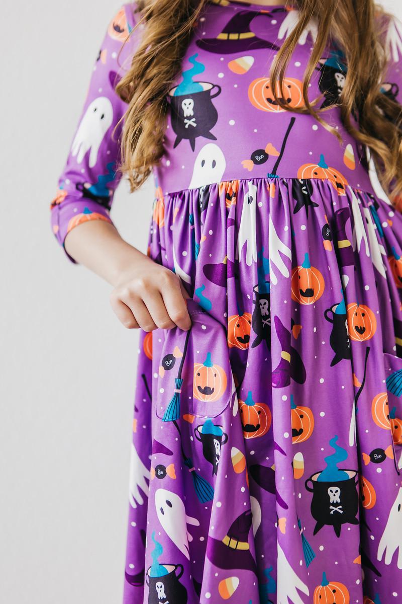 a girl wearing a purple dress with pumpkins and ghosts