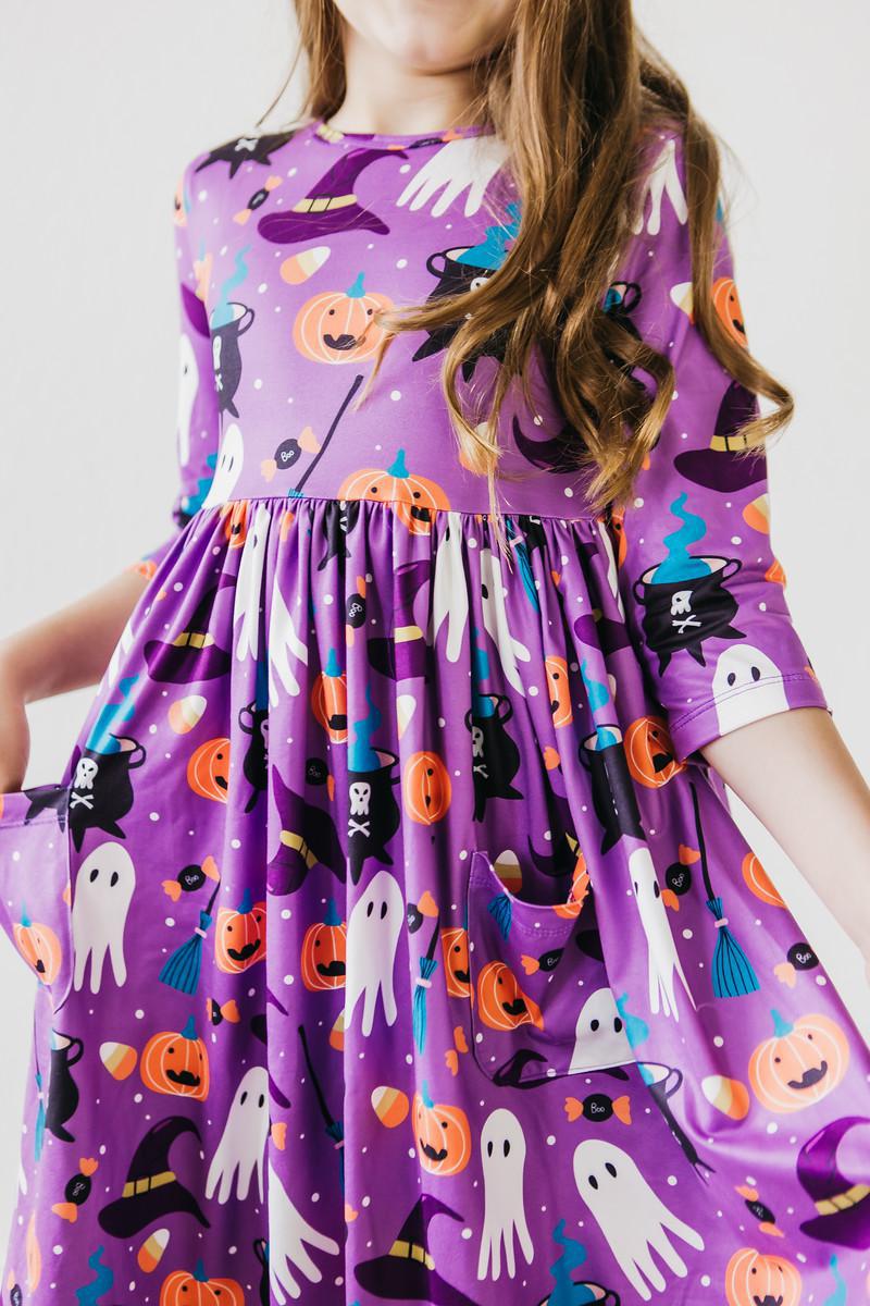 a girl wearing a purple dress with pumpkins and ghosts