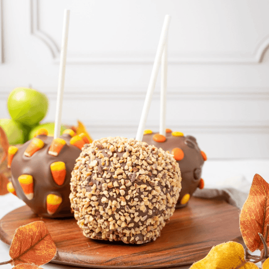 a group of chocolate apples on a wooden plate