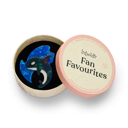 a round box with a blue and green whale brooch in it