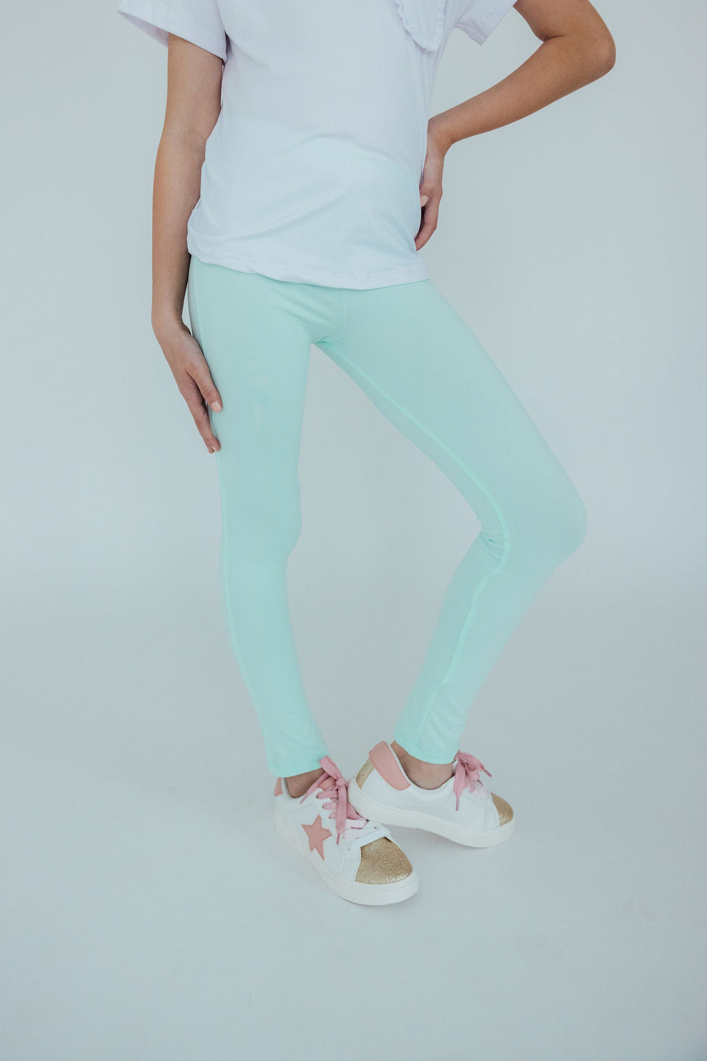 a woman wearing light blue pants and white sneakers