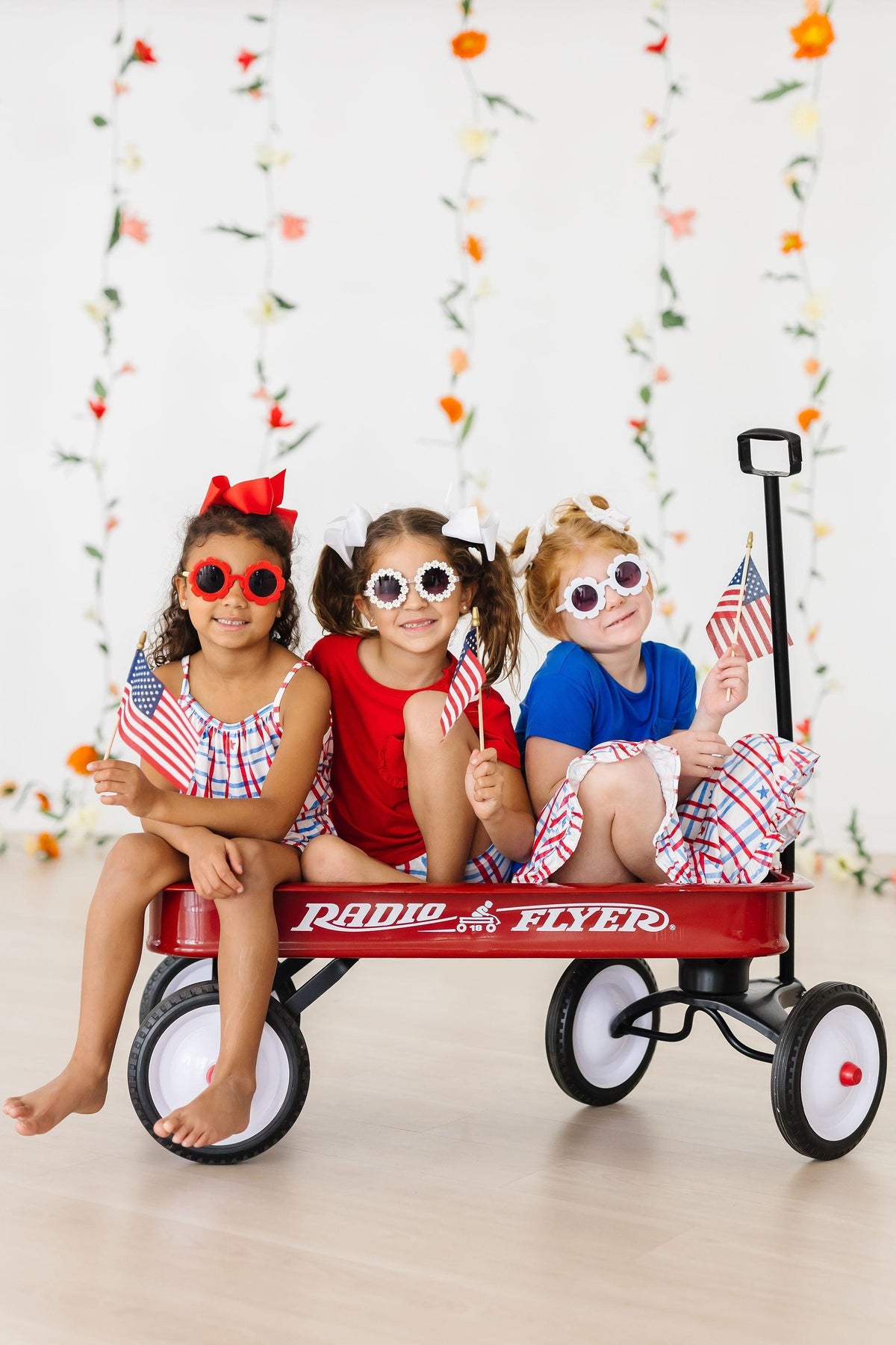 a group of girls sitting on a red wagon with flags