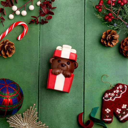 a candy bear in a box surrounded by christmas decorations